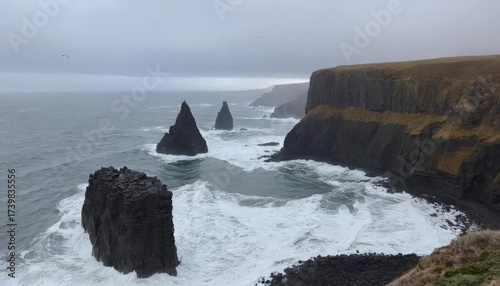Coastal cliffs meet the ocean, with waves crashing against rock formations under an overcast sky.