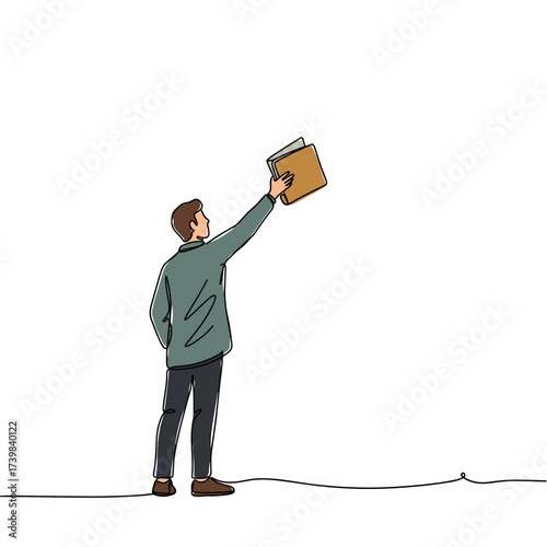 Man holding book up while standing with a neutral background  