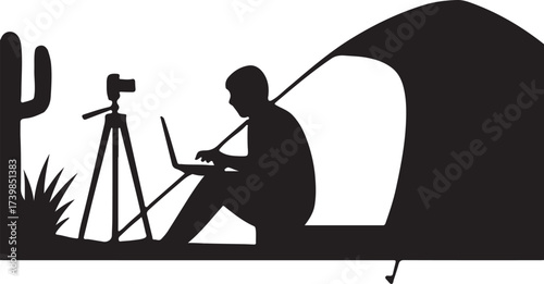 Silhouette of a person working on a laptop next to a camera on a tripod inside a tent in a desert landscape