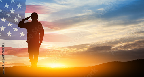 Silhouette of soldier saluting on background of sunset or sunrise and USA flag. Greeting card for Veterans Day, Memorial Day, Independence Day. America celebration.