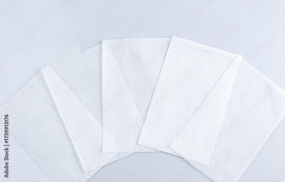 Obraz premium Several white paper sheets are positioned neatly on a light grey surface, suitable for crafts, printing, or note-taking. Their clean appearance offers versatility for many uses.
