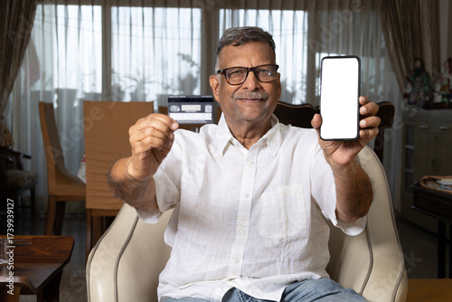 Quadro em tela Indian senior mature man presenting phone screen and debit or credit card at hom