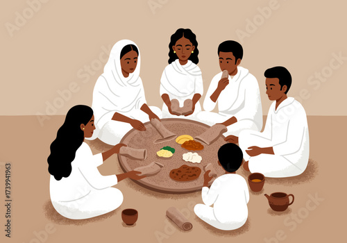 Family seated around a large platter sharing injera and stews dressed in white clothing