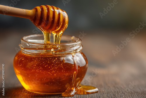 Golden Honey Dripping from Wooden Dipper into Glass Jar