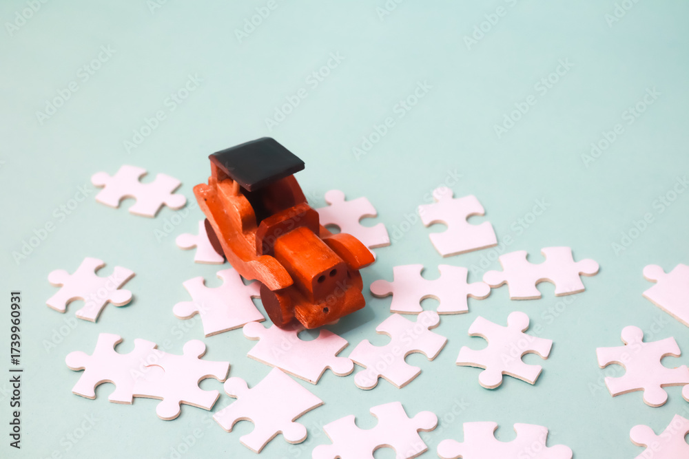 Obraz premium Creative Toy Arrangement Featuring a Wooden Car and Puzzle Pieces on Blue Background