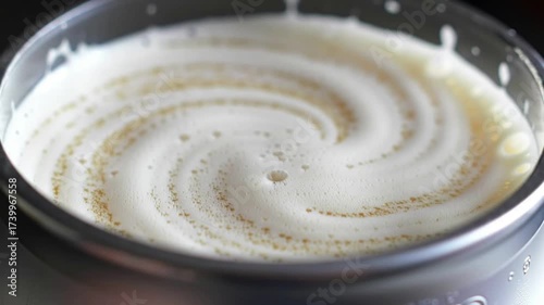 A mesmerizing close-up of creamy white froth forming a perfect spiral vortex in a bowl.