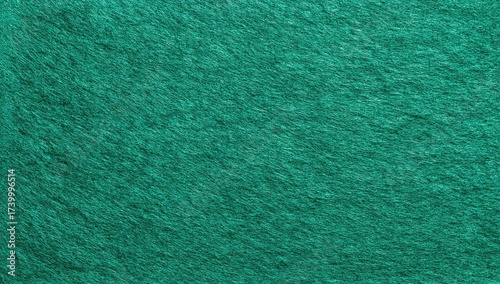 Textured, close-up shot of a teal green fabric surface. Appears soft and fuzzy