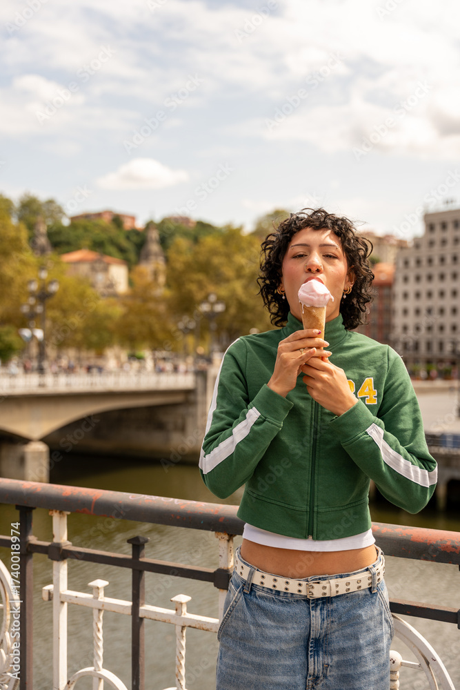 Fototapeta premium Young woman enjoying ice cream on a bridge in bilbao