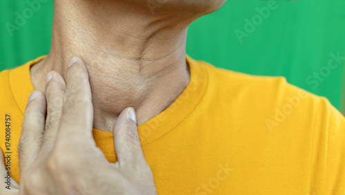 Thyroid gland inflammation at neck, goiter, throat cancer, sore throat and cough, man with neck pain on green, neck health problems concept