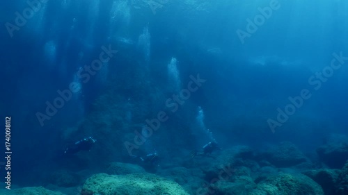 scuba divers are exploring reefs and topography underwater big rocks mediterranean sea