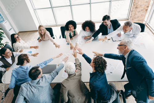 Photos Diverse team joining hands in a collaborative office meeting showcasing teamwork