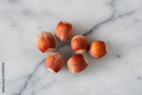 Close-up of hazelnuts in their shells on white marble