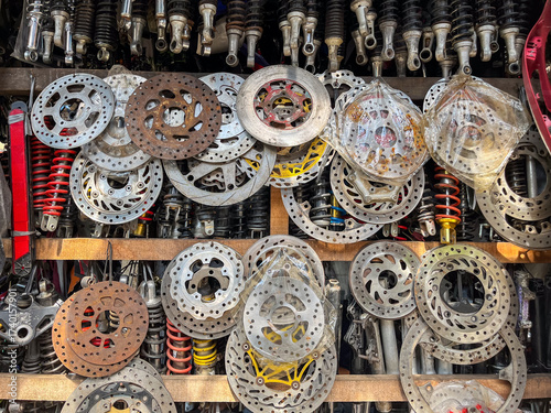 Foto Stacks of used motorcycle brake discs displayed in scrap shop, showcasing worn metal textures and mechanical variety in secondhand automotive parts market environment