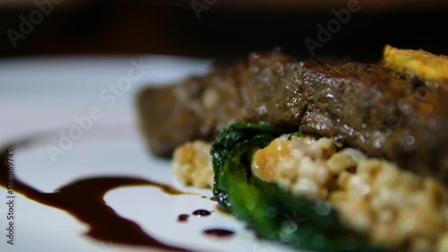 Medium rare beef steak with spinach and butter on wheat porridge on white plate gourmet meal close up food photography.