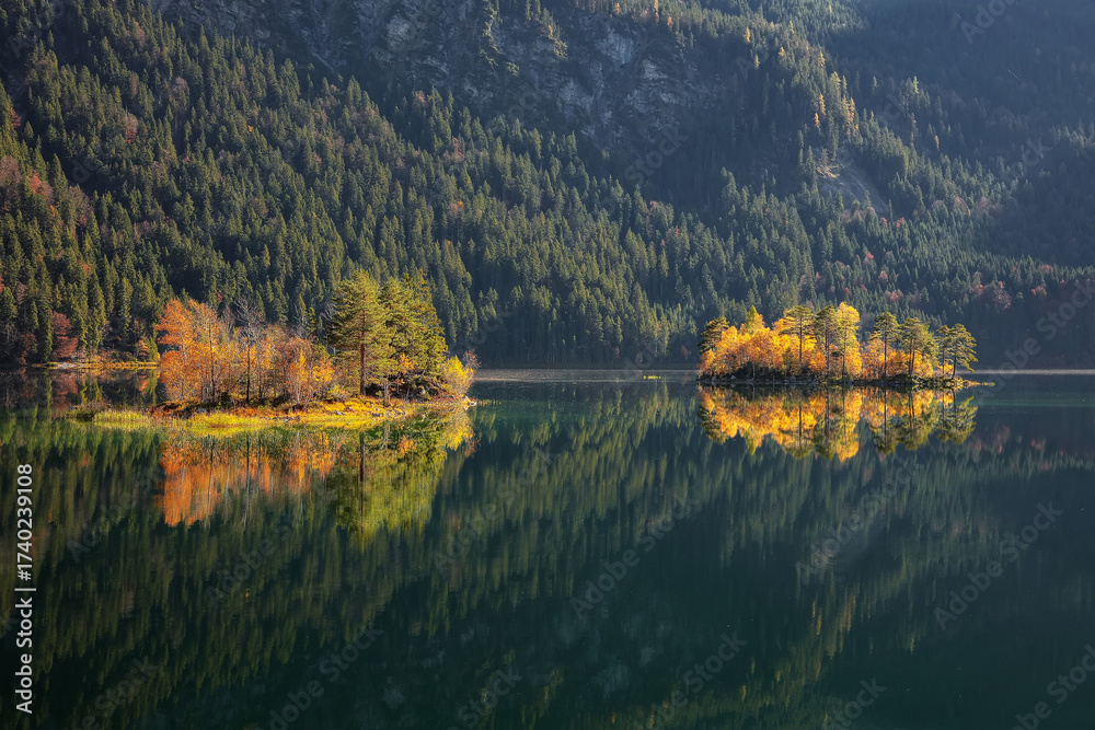 Fototapeta premium Fabulous autumn landscape of islands with pine-trees in the middle of Eibsee lake.