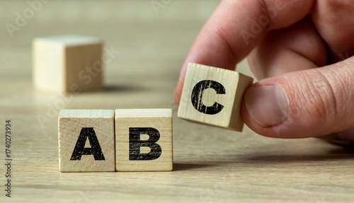 A hand moves a wooden block with the letter C to spell ABC, representing the basics of learning and education. Ideal for teaching and childhood concepts.