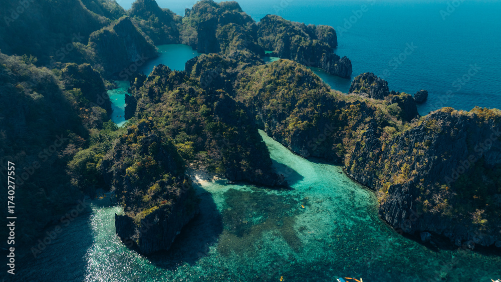 Fototapeta premium Scenic view of a blue lagoon over the calm sea with dark rocks in silhouette, creating a peaceful and natural coastal landscape.