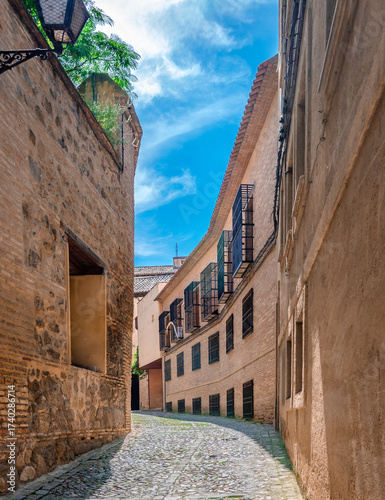 Narrow cobblestone alley in the old historic center of Toledo, in Castilla-La Mancha, Spain.