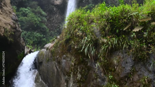 Cascada El Rocio Machay waterfall near Banos de Agua Santa in Ecuador. Majestic waterfall cascades down rocky cliff, creating a serene pool surrounded by lush greenery and smooth stones