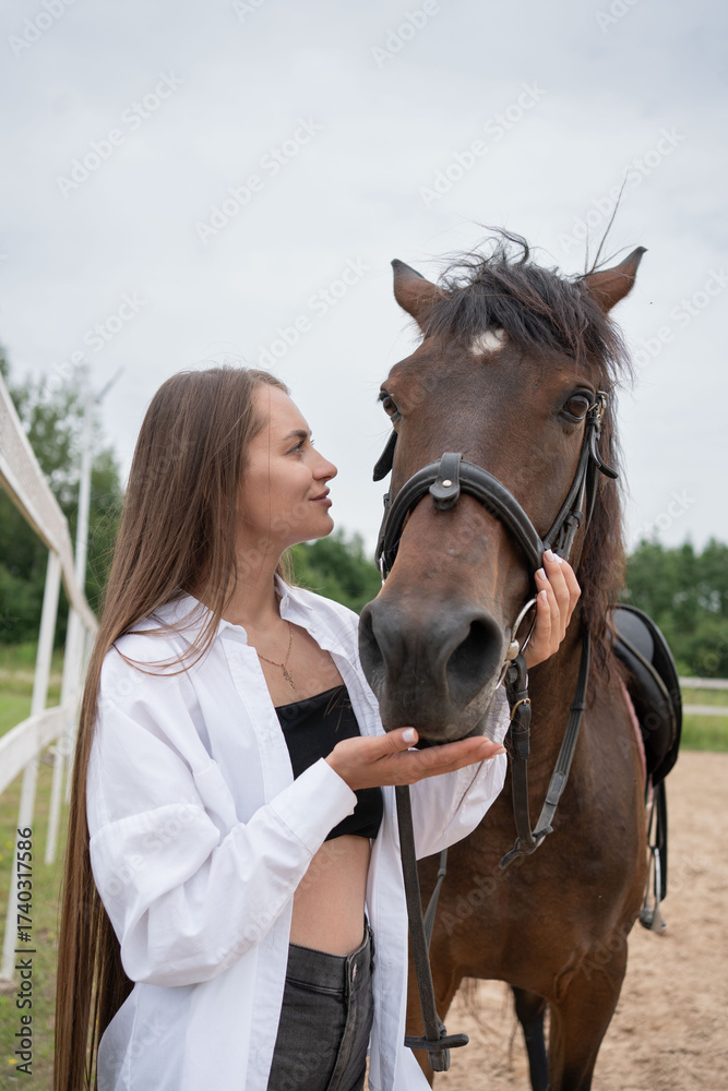 Obraz premium Tender moment between a young woman and a horse in a stable, highlighting a serene and emotional connection.