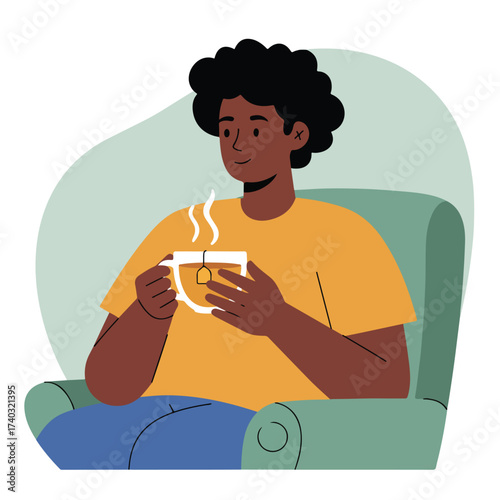 Person relaxing in armchair, enjoying hot beverage in a mug with steaming tea bag