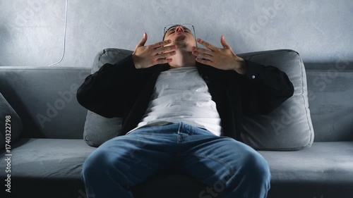 A man in a black shirt and jeans sits on a sofa, taking deep breaths to calm down and relax.
Nerves and stress.
Breathing practices and meditation.
Yoga at home.
Mental health