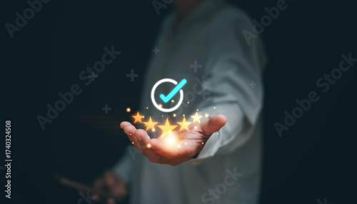 Customer satisfaction concept. Client's hand holding glowing five stars with a checkmark icon above. Symbolizing service quality, trust, positive experience and successful brand reputation.