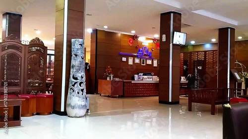 A cozy hotel lobby in the early morning, softly illuminated by warm sunlight streaming through large windows. The atmosphere feels calm and welcoming, with comfortable sofas, elegant décor, and fresh 