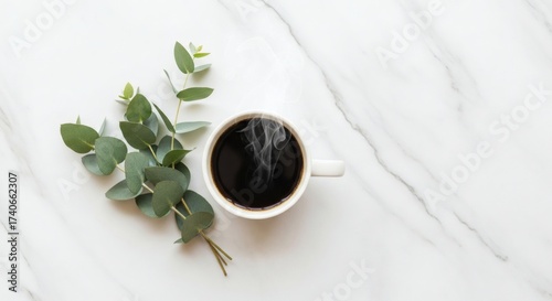 Minimalist coffee cup on marble beside eucalyptus leaves