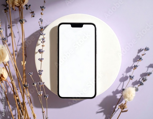 Smartphone on a white podium, surrounded by dried flowers
