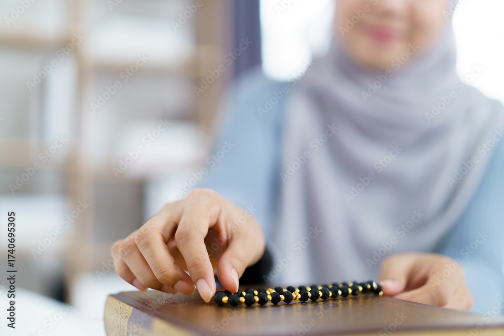 Fototapeta premium Muslim woman meditating and praying in morning light holding prayer beads.