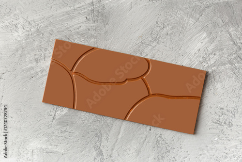 Chocolate with a beautiful pattern on a gray texture background, top view.