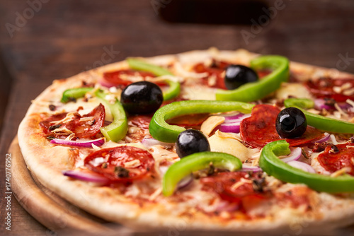Pizza with chorizo ​​sausage, mozzarella cheese, green pepper and black olives. Rustic wooden background. Soft focus.	