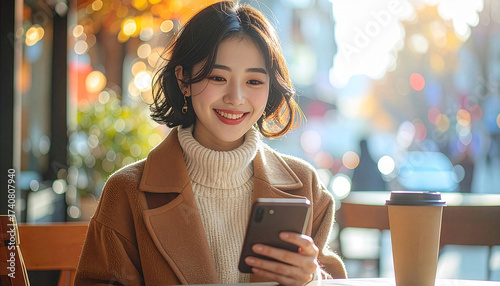 Smiling young woman using smartphone at outdoor cafe in autumn