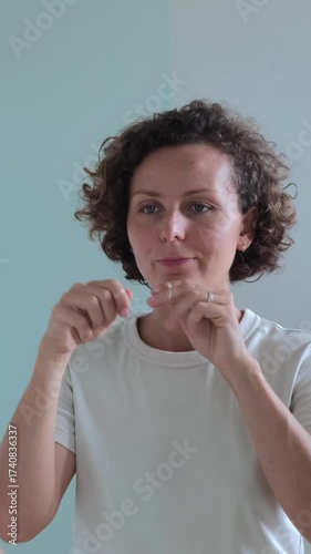 Young woman with curly hair diligently flossing her teeth as part of her daily oral hygiene routine, promoting dental health and preventing gum disease with interdental cleaning