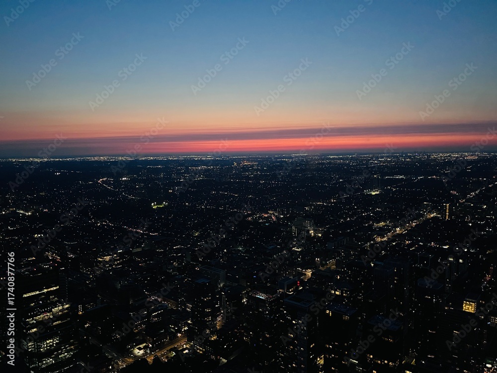 Fototapeta premium Aerial wide shot of Toronto city lights at night with sunset horizon