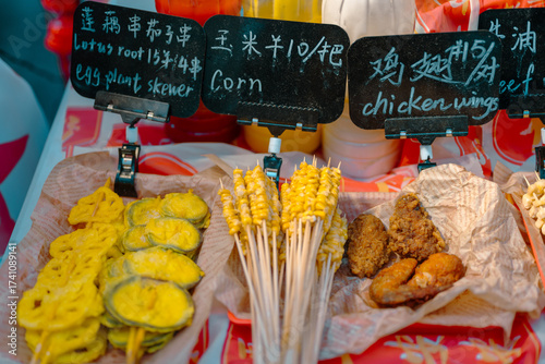 Guangzhou, Canton, China. street food stall with corn skewers, lotus root, eggplant and fried chicken wings showing Chinese culinary culture and urban lifestyle