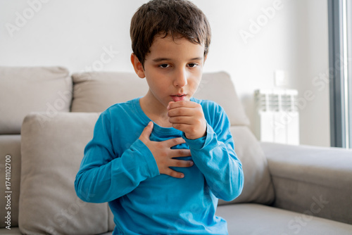 Valokuva Child sitting on sofa at home and holding hand on chest