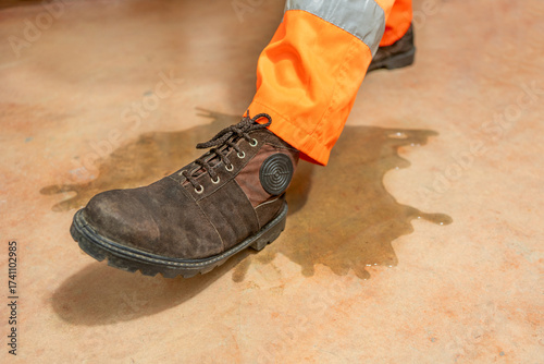 An industrial, manufacturing, safety topic. A worker slipping on liquid.