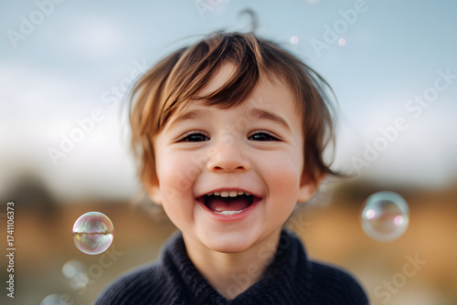 A happy child laughing with bubbles floating around him