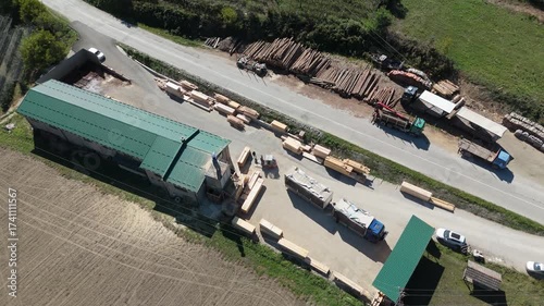 Aerial view of a sawmill factory in the mountains surrounded by dense forest, with stacks of processed lumber and timber. Wood industry and natural resource production	