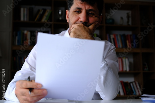 Tablou pe pânză bored, thoughtful and worried businessman checking paperwork about contracts, ex