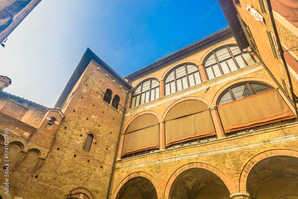 Obraz premium Photo of a typical building facade in Siena old town showing medieval stone and brick architecture, rustic windows with shutters and authentic Tuscan atmosphere in Italy
