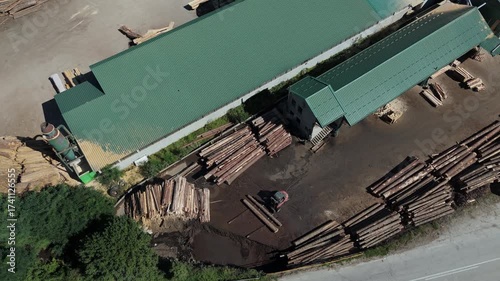 Aerial view of a sawmill factory in the mountains surrounded by dense forest, with stacks of processed lumber and timber. Wood industry and natural resource production	