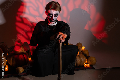 Photography Man is sitting on the floor,holding a staff,with Halloween-themed pumpkins