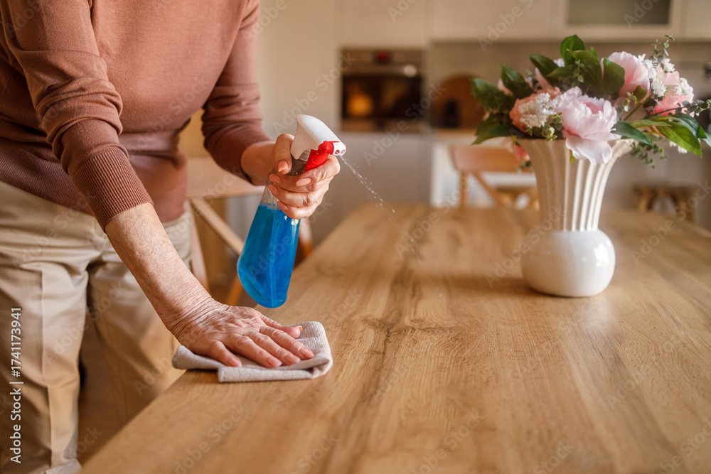 Φωτογραφία Midsection of elderly woman spraying cleaner on wooden dining table and wiping w