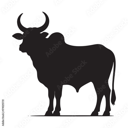 Silhouette of a majestic bull with prominent horns standing on a grassy field