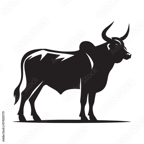 Silhouette of a majestic bull with prominent horns standing on a grassy field