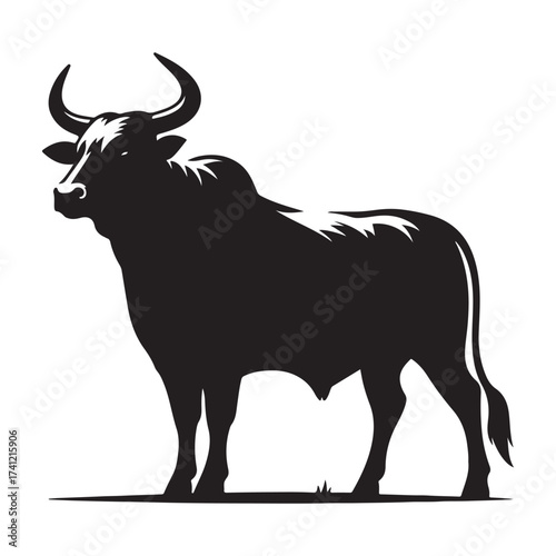 Silhouette of a majestic bull with prominent horns standing on a grassy field