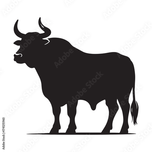 Silhouette of a majestic bull with prominent horns standing on a grassy field